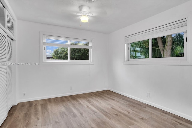 unfurnished bedroom featuring multiple windows, wood finished floors, baseboards, and a closet