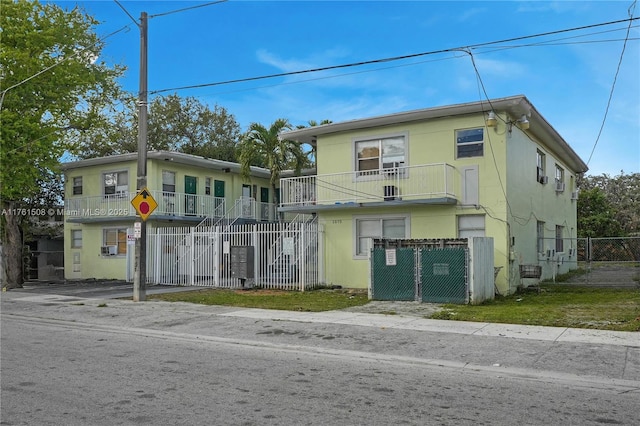 view of front of home featuring a balcony, a gate, cooling unit, and a fenced front yard