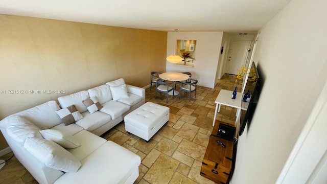 living area featuring stone tile floors and baseboards