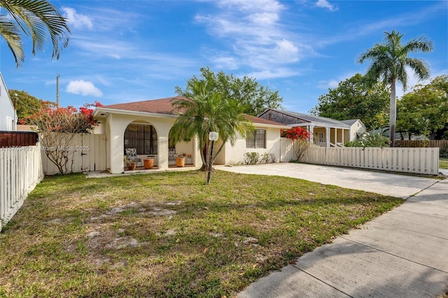 view of front of property with a patio, driveway, stucco siding, a front lawn, and fence private yard