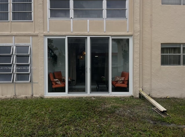 property entrance with a lawn and stucco siding