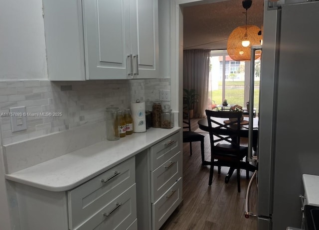 kitchen with light countertops, freestanding refrigerator, tasteful backsplash, and dark wood finished floors