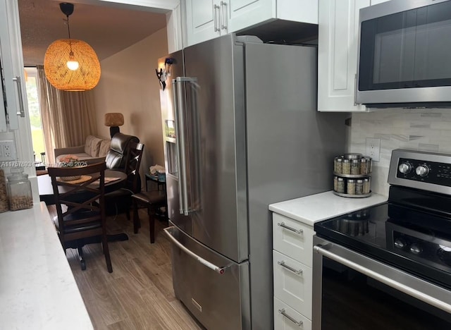 kitchen featuring light wood-style flooring, backsplash, stainless steel appliances, white cabinets, and light countertops