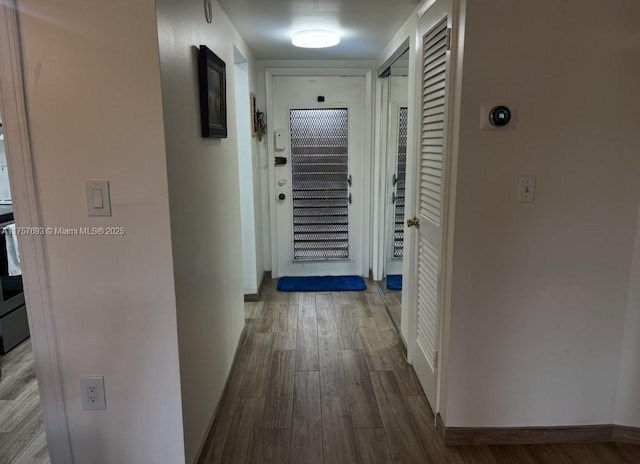 corridor featuring dark wood-type flooring and baseboards