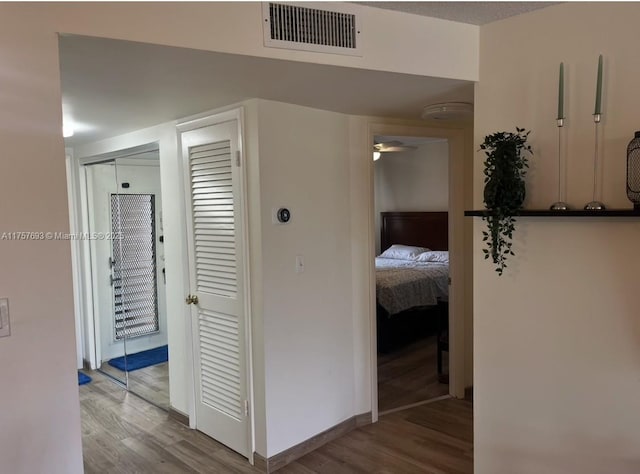 hallway featuring baseboards, wood finished floors, and visible vents