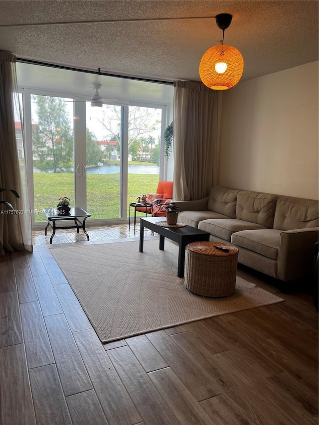living room with wood finished floors, a textured ceiling, and a water view