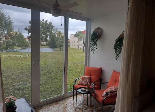 sunroom / solarium with ceiling fan and a water view
