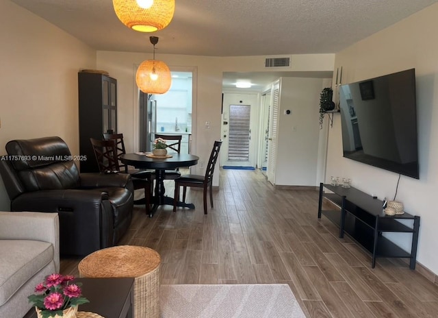 living room with visible vents, baseboards, a textured ceiling, and wood tiled floor