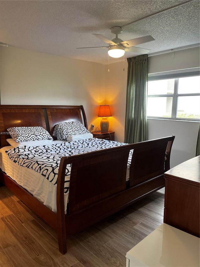 bedroom featuring ceiling fan, wood finished floors, and a textured ceiling