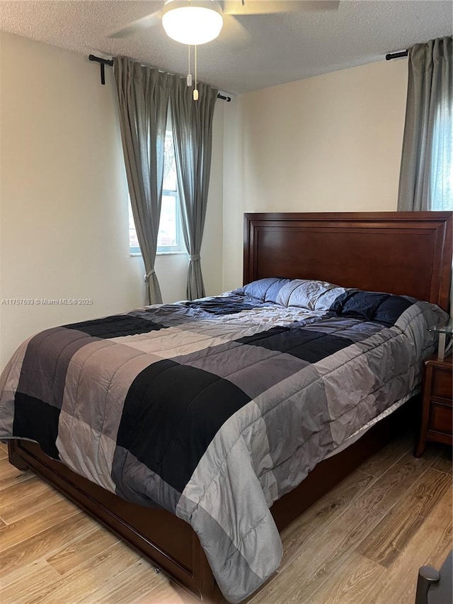 bedroom with wood finished floors, a textured ceiling, and ceiling fan