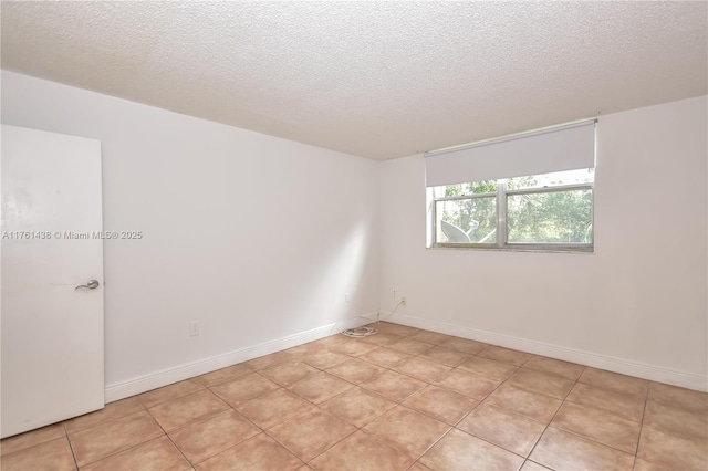 unfurnished room featuring light tile patterned flooring, baseboards, and a textured ceiling