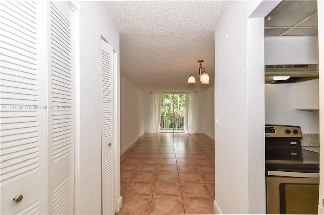 corridor with baseboards, a textured ceiling, an inviting chandelier, and light tile patterned flooring