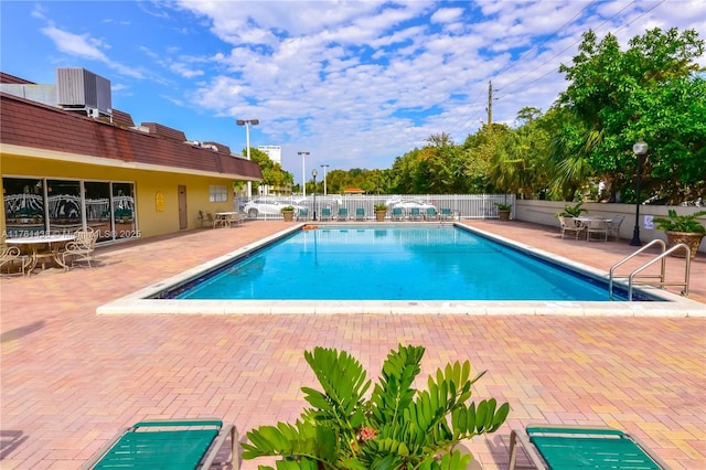 community pool featuring a patio area, central air condition unit, and fence