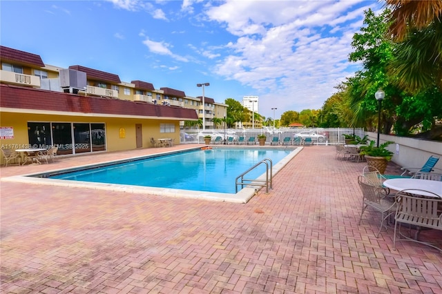 community pool with a patio and fence