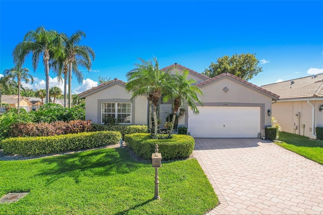 view of front of house with a front yard, decorative driveway, a garage, and stucco siding