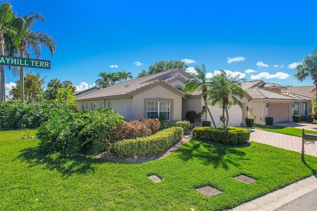 view of front of house featuring stucco siding, a front lawn, a tile roof, decorative driveway, and an attached garage