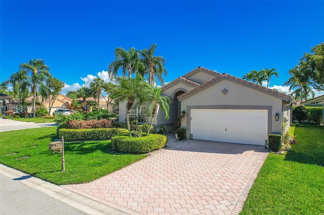 view of front of house featuring a tile roof, a front yard, stucco siding, decorative driveway, and an attached garage