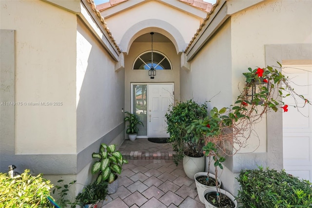 entrance to property featuring stucco siding, a garage, and a tile roof