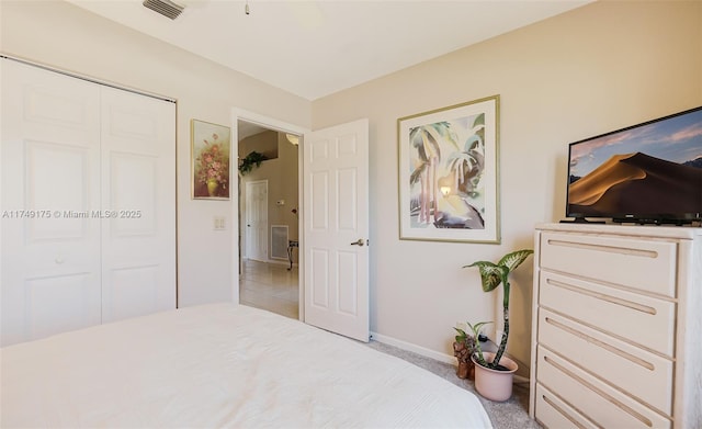 carpeted bedroom with visible vents, baseboards, and a closet