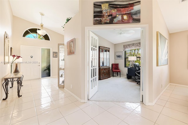 entryway with light tile patterned flooring, light carpet, baseboards, and vaulted ceiling