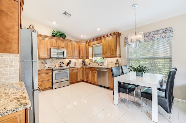 kitchen featuring visible vents, backsplash, vaulted ceiling, stainless steel appliances, and a sink