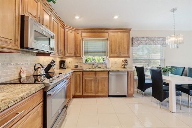 kitchen featuring light stone countertops, light tile patterned flooring, a sink, decorative backsplash, and stainless steel appliances