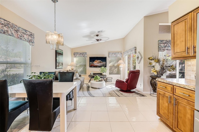 dining space with lofted ceiling, light tile patterned floors, ceiling fan with notable chandelier, and baseboards