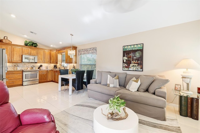 living area with vaulted ceiling, light tile patterned flooring, visible vents, and a chandelier