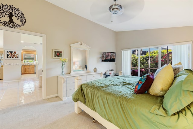 bedroom with multiple windows, light carpet, arched walkways, and vaulted ceiling