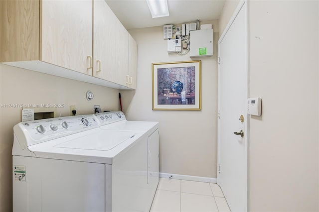 washroom featuring washer and dryer, light tile patterned floors, cabinet space, and baseboards