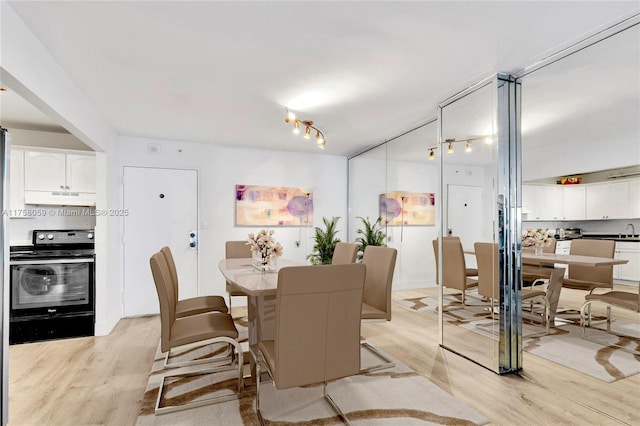 dining area with track lighting and light wood-style flooring