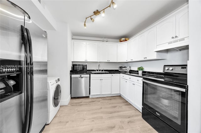 kitchen featuring under cabinet range hood, light wood-type flooring, washer / dryer, black appliances, and a sink