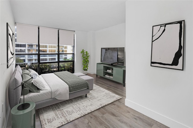 bedroom featuring wood finished floors, baseboards, and expansive windows