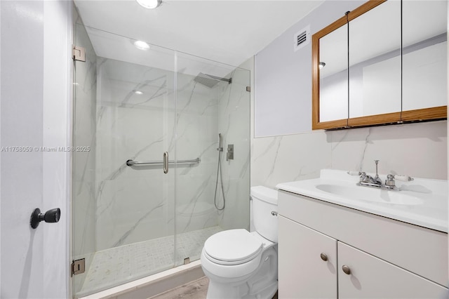 bathroom featuring vanity, visible vents, a marble finish shower, tile walls, and toilet