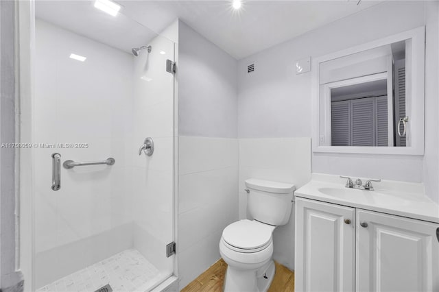 bathroom with visible vents, toilet, a stall shower, wood finished floors, and vanity