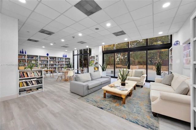 living area featuring a wall of windows, wood finished floors, visible vents, and a drop ceiling