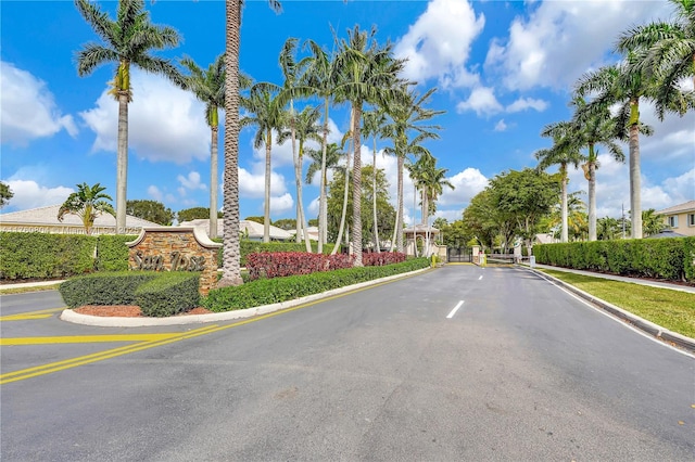 view of road with a gated entry, curbs, and sidewalks