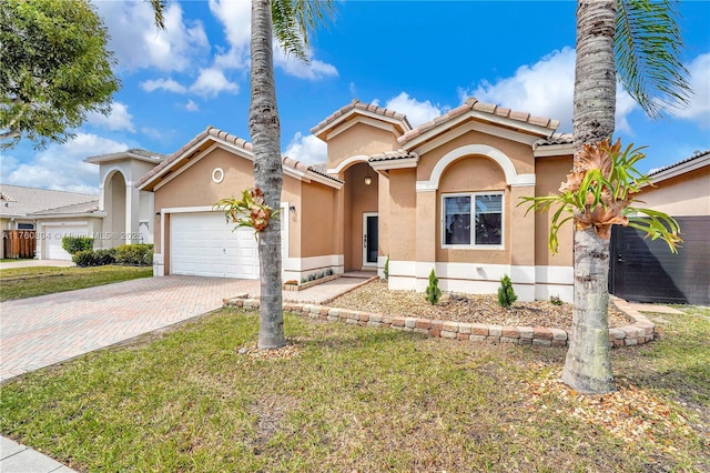 mediterranean / spanish house with a front yard, decorative driveway, a garage, and stucco siding