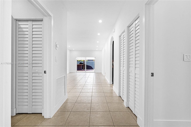 hall featuring light tile patterned floors, visible vents, recessed lighting, and arched walkways