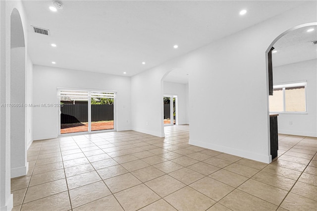 unfurnished room with visible vents, recessed lighting, arched walkways, light tile patterned floors, and baseboards