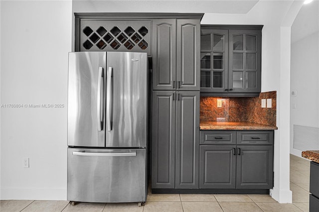 kitchen with light tile patterned floors, glass insert cabinets, gray cabinetry, and freestanding refrigerator