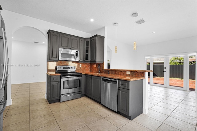 kitchen featuring visible vents, a peninsula, gray cabinets, stainless steel appliances, and backsplash