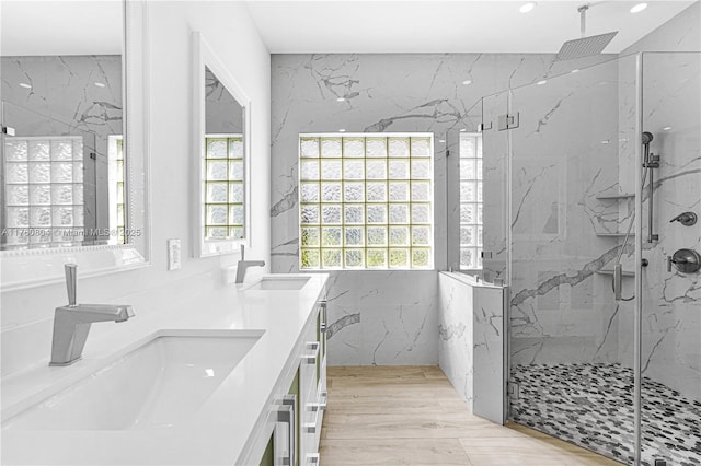 bathroom with double vanity, wood finished floors, a marble finish shower, and a sink