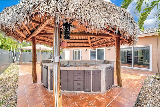 view of patio with a gazebo, area for grilling, a fenced backyard, and a sink