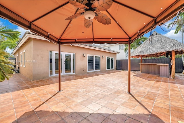 view of patio featuring a gazebo, french doors, a ceiling fan, and fence