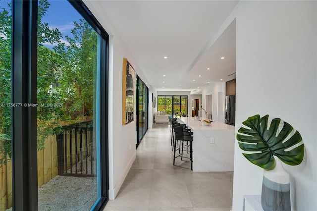 hallway with a sink, recessed lighting, and light tile patterned floors