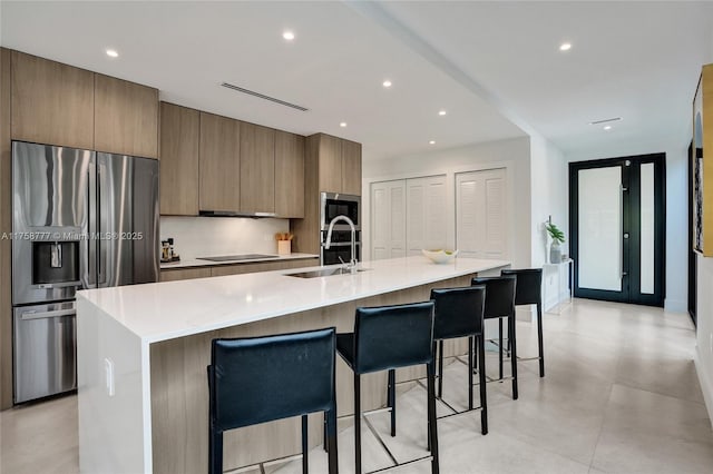 kitchen featuring a sink, modern cabinets, appliances with stainless steel finishes, and a breakfast bar