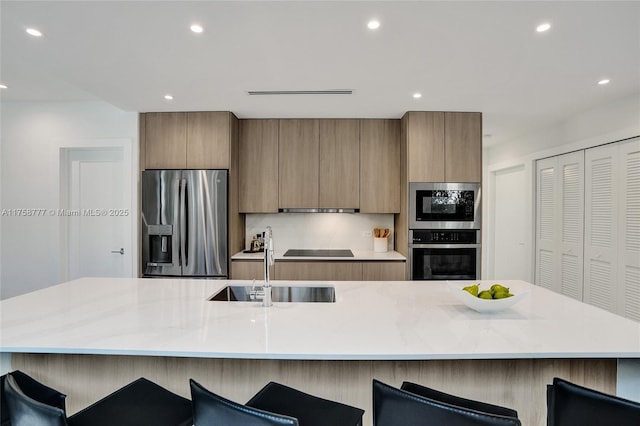 kitchen featuring a large island with sink, a sink, appliances with stainless steel finishes, modern cabinets, and recessed lighting