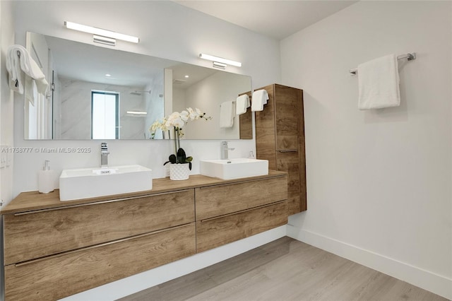 bathroom featuring double vanity, a sink, baseboards, and wood finished floors