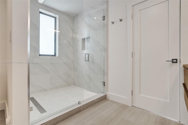 full bathroom featuring a marble finish shower and wood finished floors